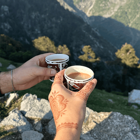 Mona und Arian stoßen mit Chai-Bechern im Himalaya an – authentische Chai-Kultur erleben mit Henna-Händen als Reise-Inspiration für Mangala Chai